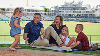 The Burchett family sitting on a blanket at the Frisco baseball stadium.