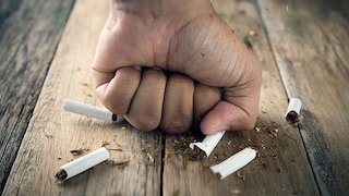 Fist punching cigarettes on a table