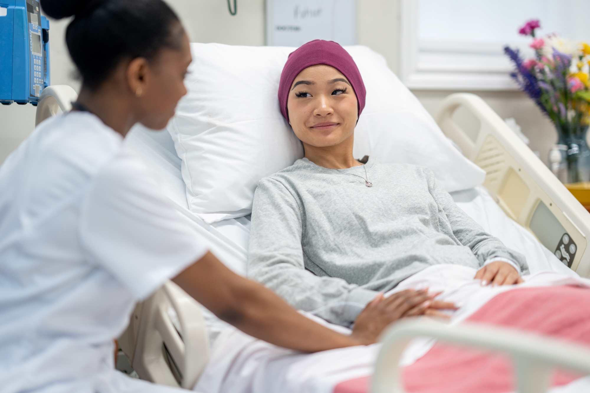 Woman in hospital bed getting comfort from care provider