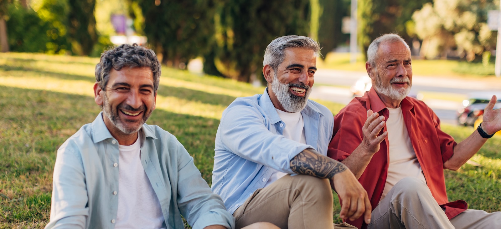 3 men sitting on the grass, smiling