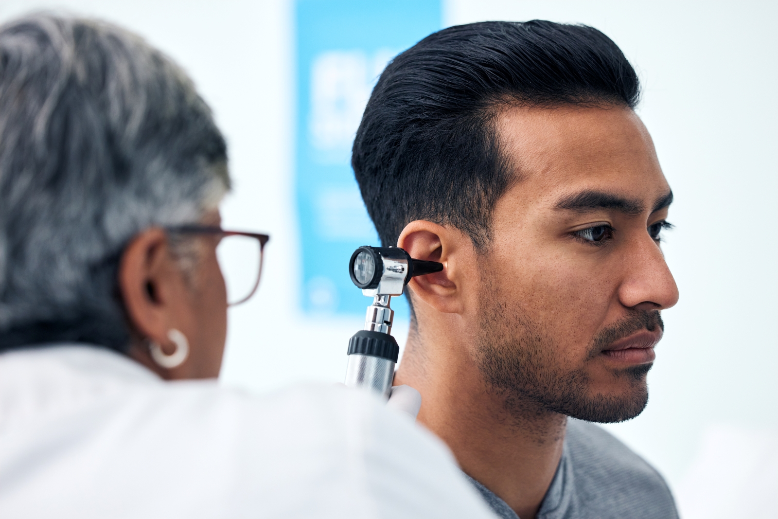Doctor is using a tool to check the inner ear of a patient.