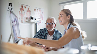 A doctor showing a patient something on a computer screen.