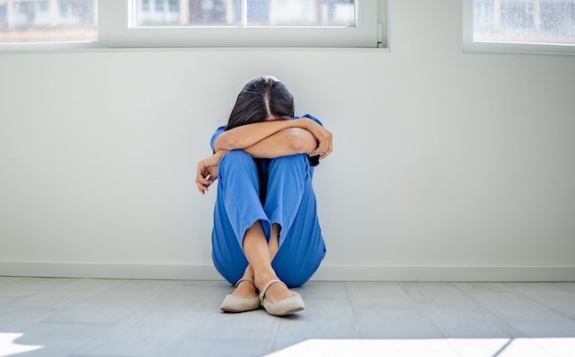 A young female worker sits on the floor, deep in thought about the demands faced life..