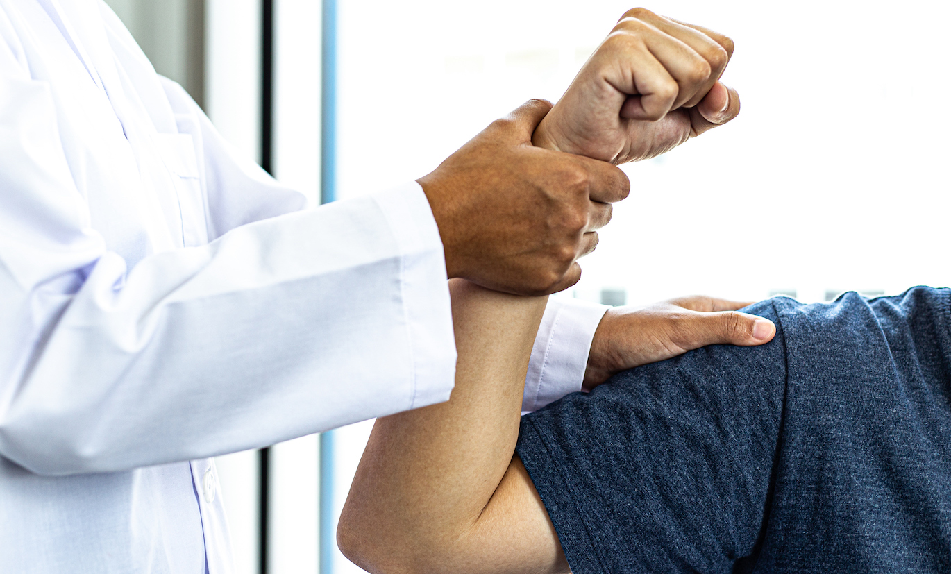 physician with hands on patient's wrist and shoulder