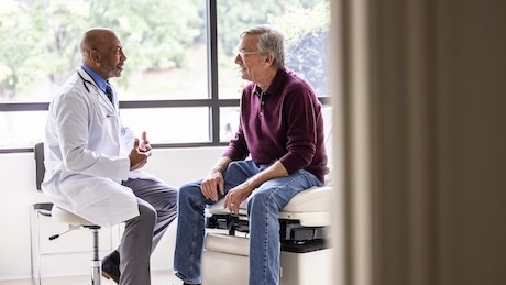 Male doctor talking with senior man in exam room