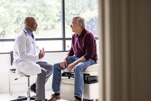 Male doctor talking with senior man in exam room