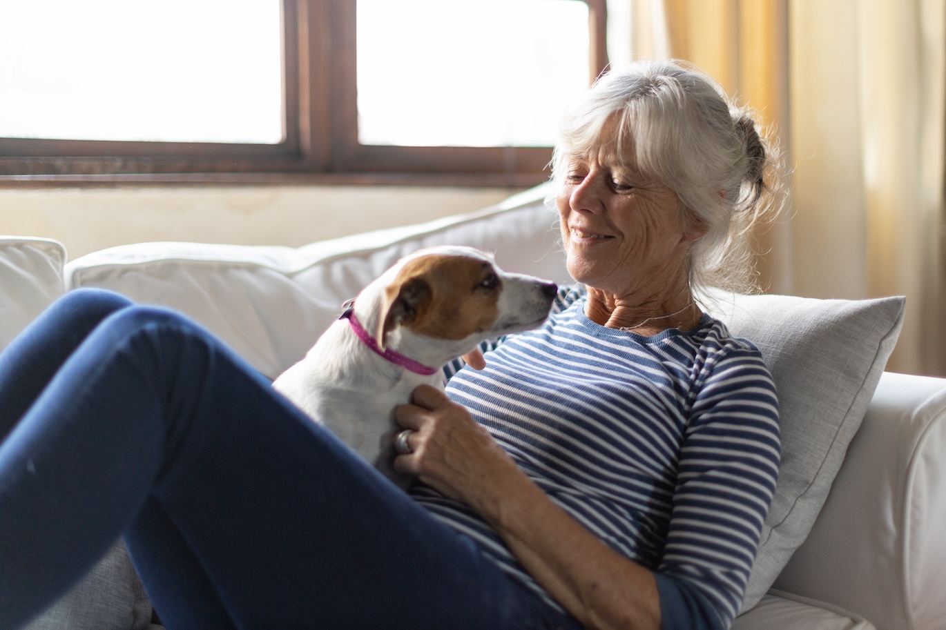 elderly woman sitting on a couch with a dog.