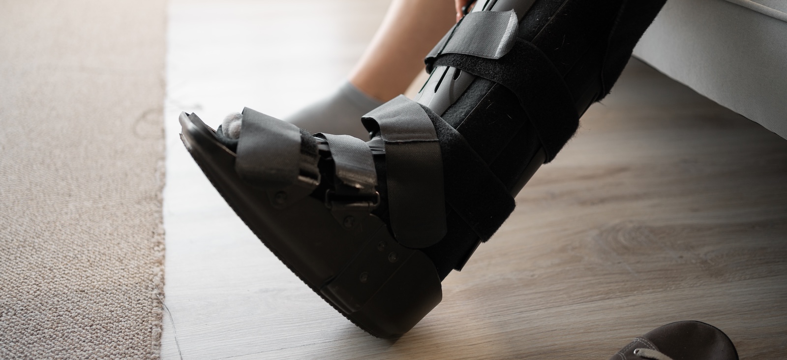 A person wearing a black orthopedic walking boot on their lower leg and foot.