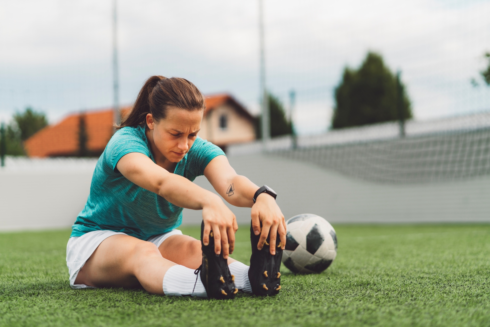 Female soccer player stretching on turf field