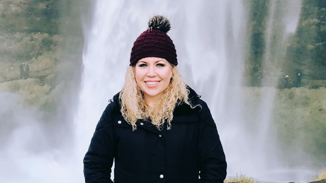 Christina Garduno at a waterfall wearing black coat and hat