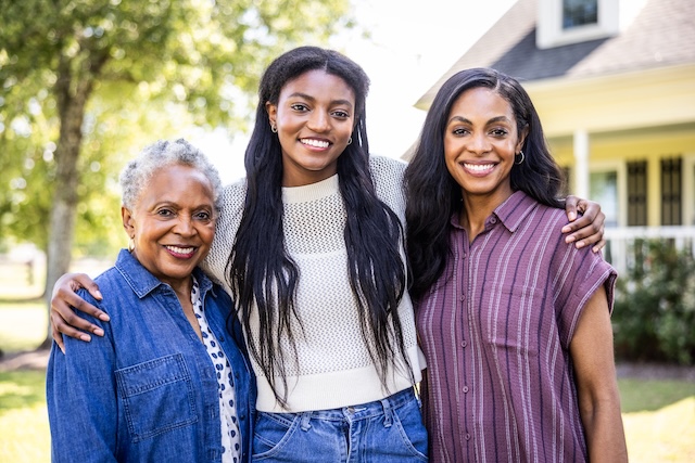 Family portrait of 3 generations of women in front of a home