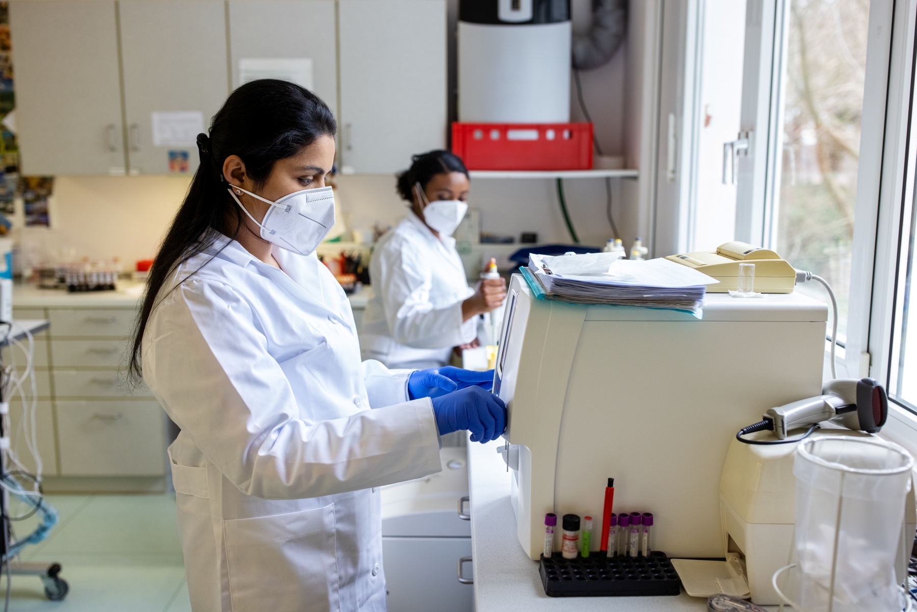 Two women wearing masks and gloves working in a science lab