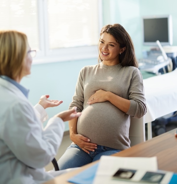 Pregnant woman talking to a doctor during a visit in the office