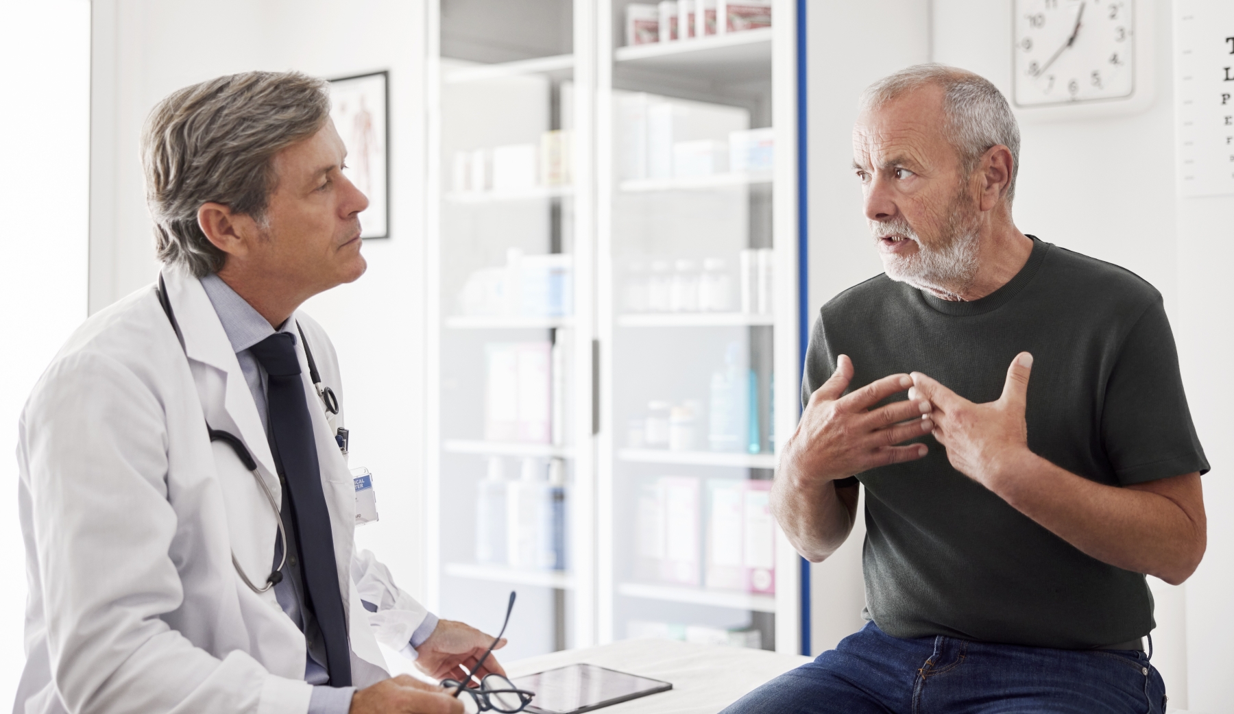 Man seated on exam table talking with doctor