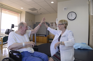 Dr. Kathleen Bell high fives a stroke patient during rehab.