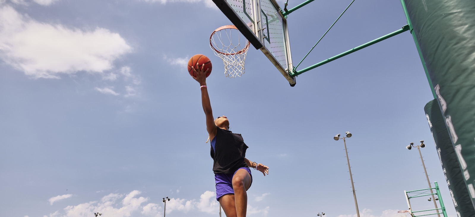 Woman shooting a layup on an outdoor basketball court