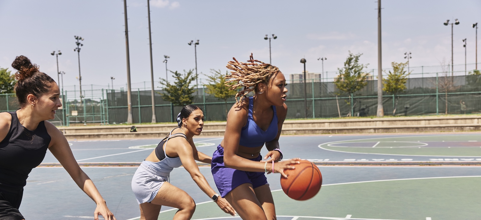 Women playing basketball on an outdoor court