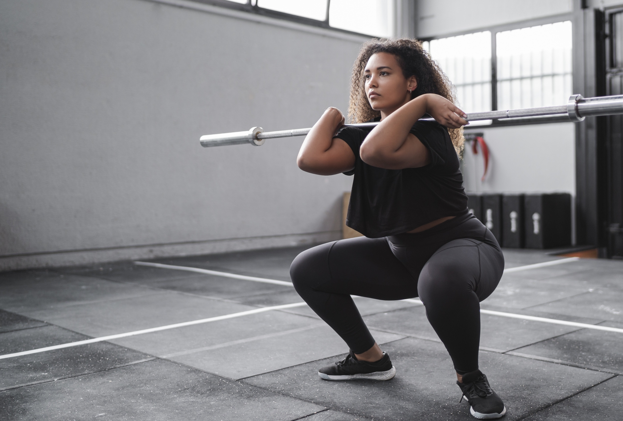 Woman in gym doing squats with barbell