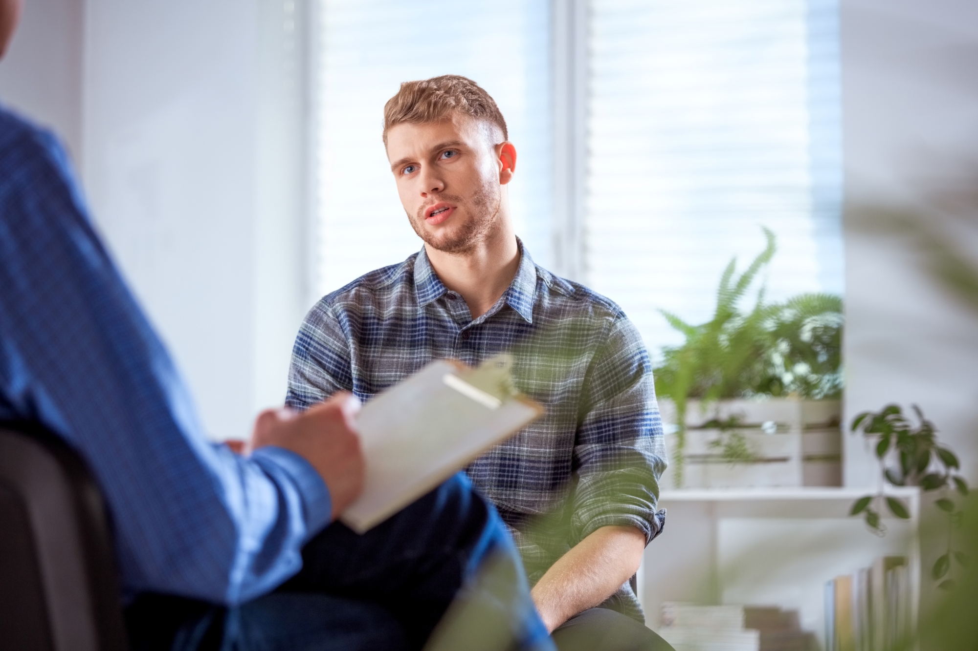 Man in his 20s seated and talking with a therapist