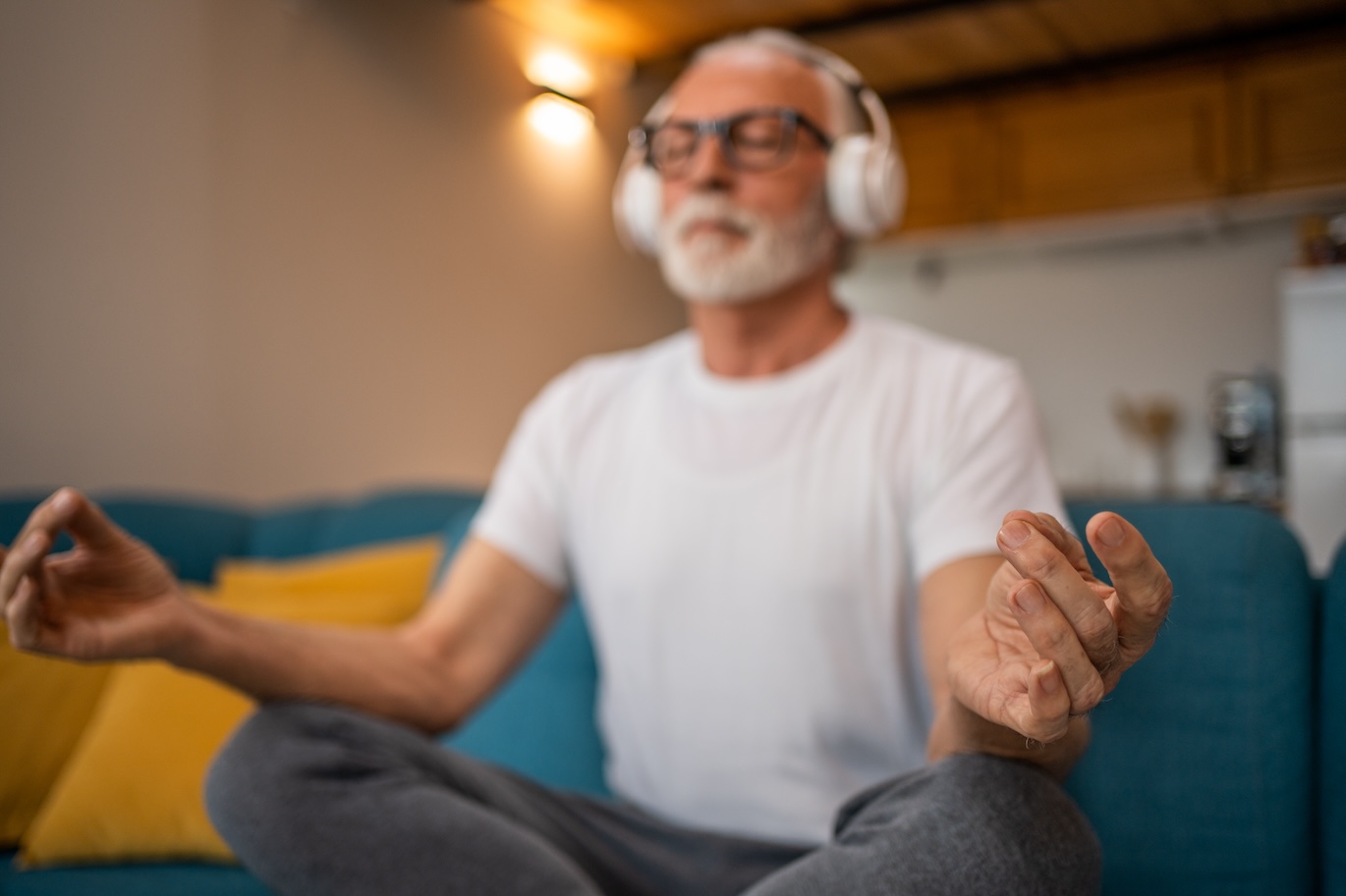 man meditating in his living room with headphones on