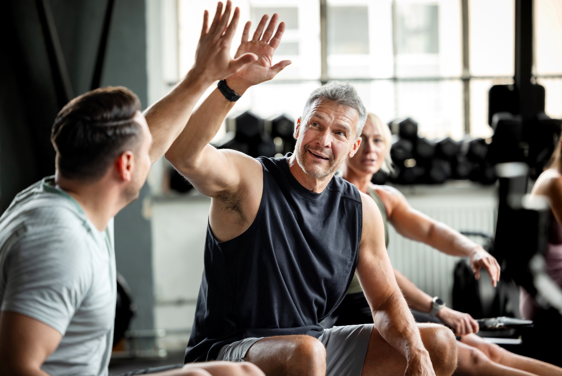 Two men sitting in gym exchanging a high five