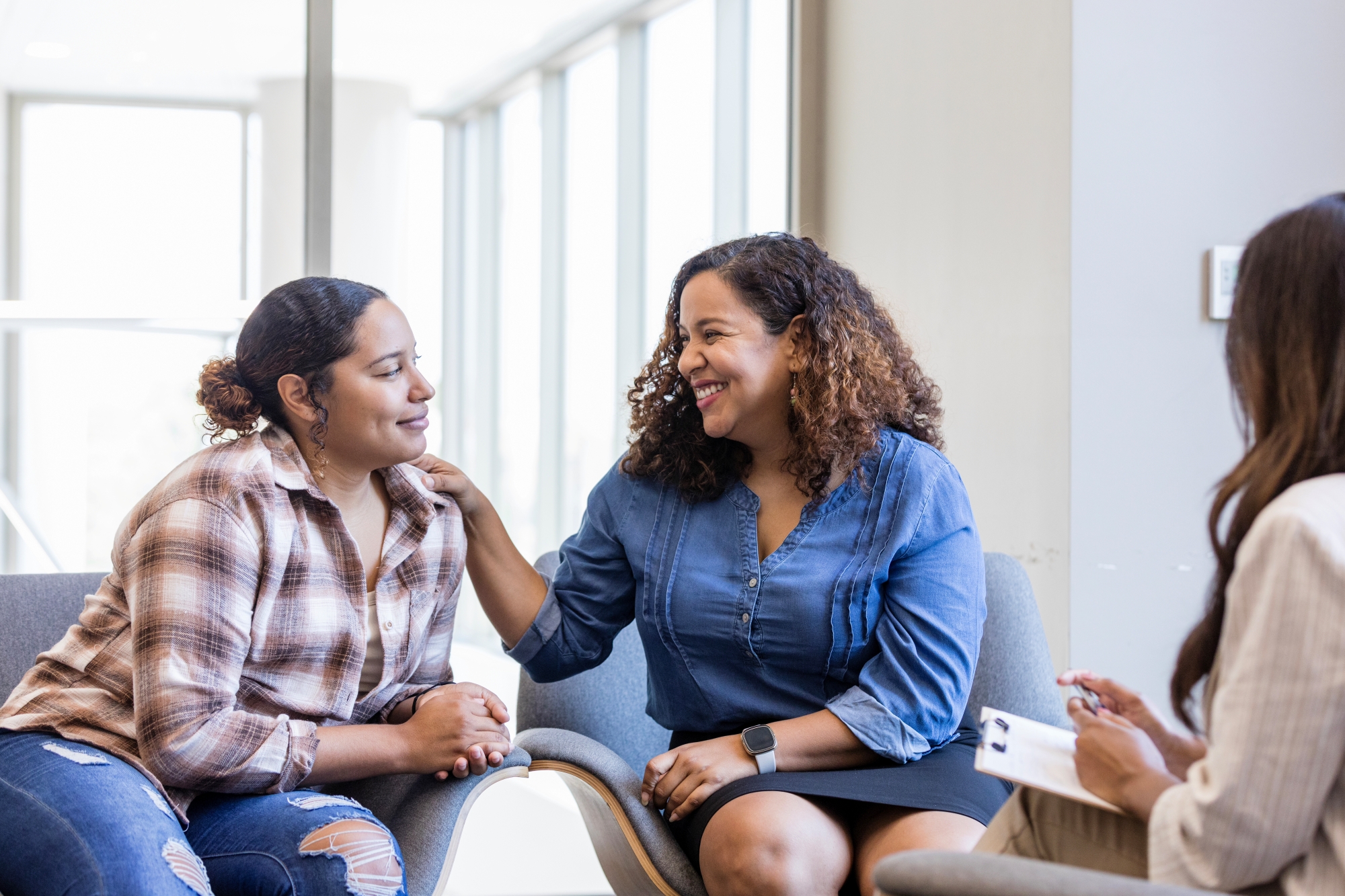 Young adult woman getting reassuring touch from mom in therapy session