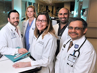 A group of healthcare professionals are shown standing together in a medical setting, wearing white coats and stethoscopes.