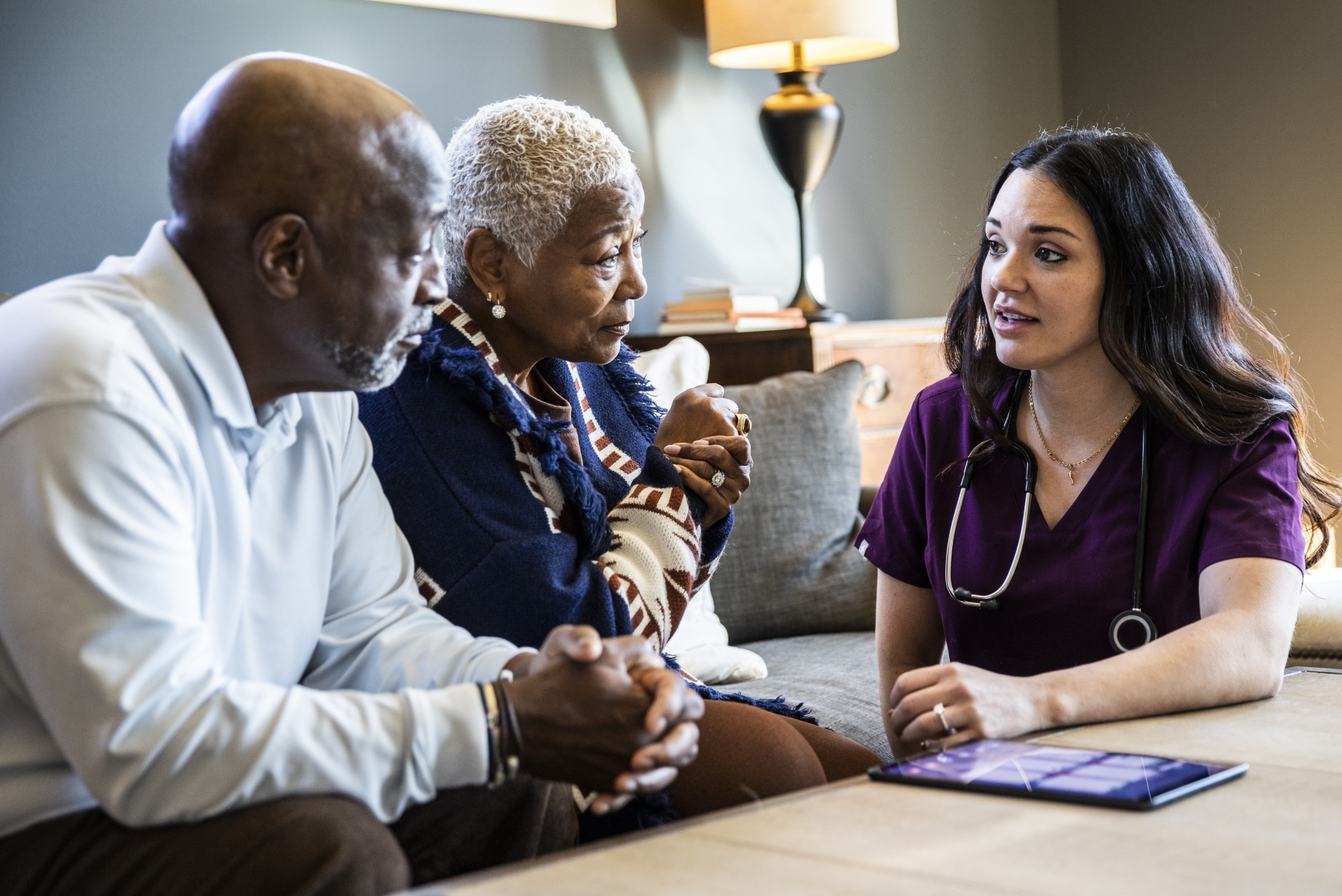 Older couple talking with visiting nurse in living room