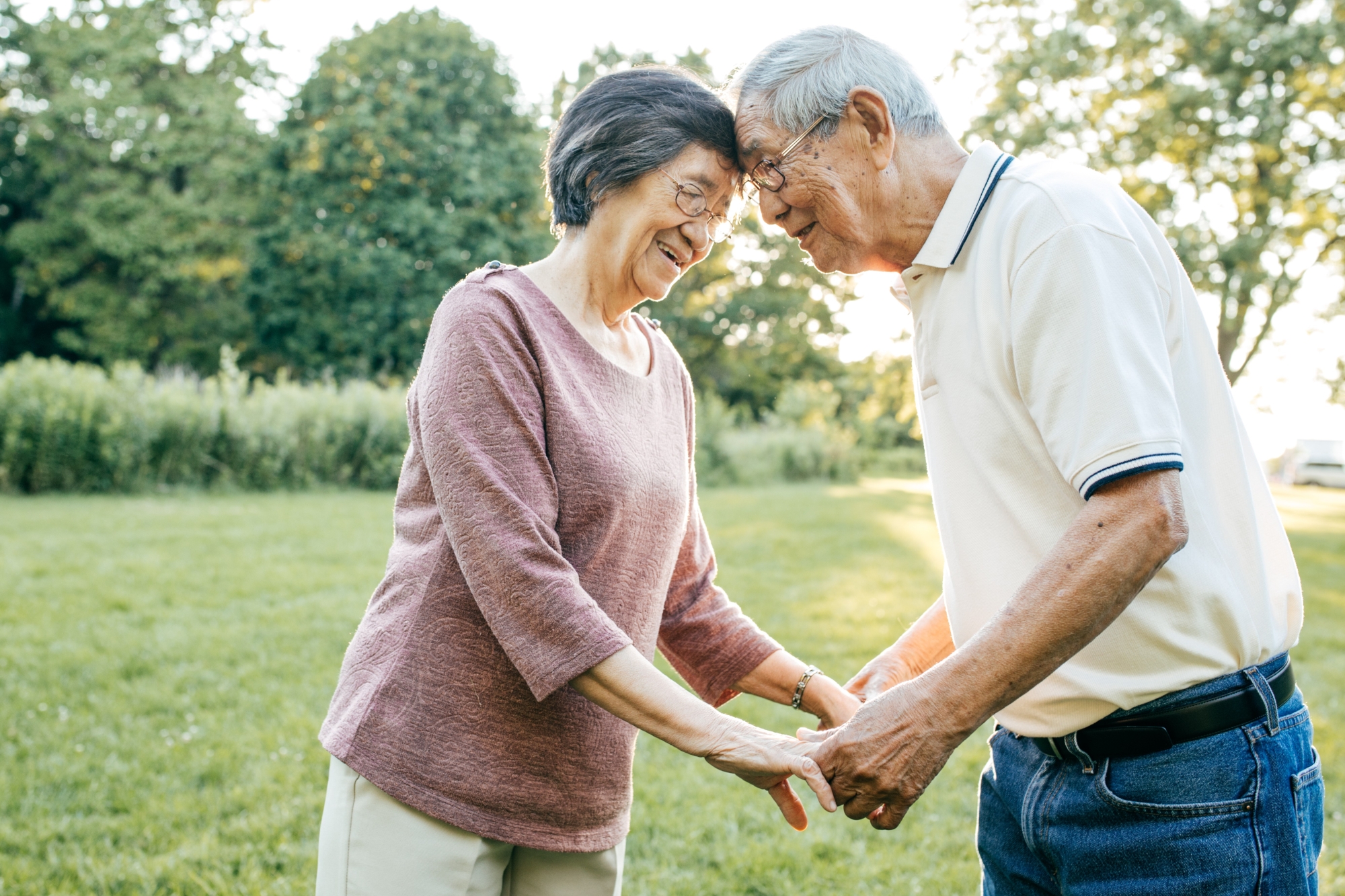 Older couple holding hands with heads together outdoors