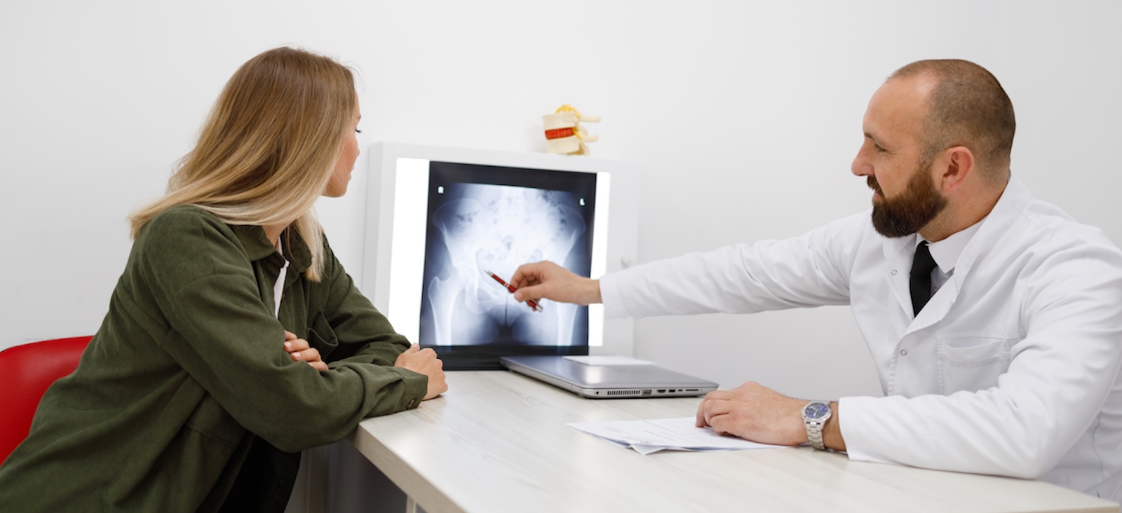 Doctor pointing at x-ray of pelvis with patient looking on