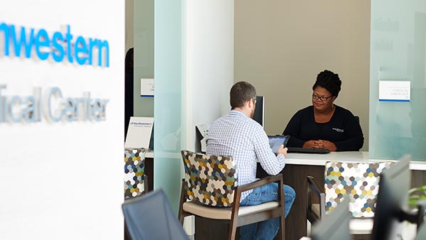 patient speaking to a UTSW employee sitting at a desk