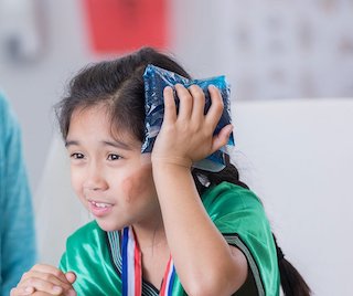 A child holding an ice pack to the side of her head.