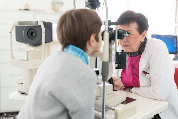 Female optician monitoring young boy in eye clinic