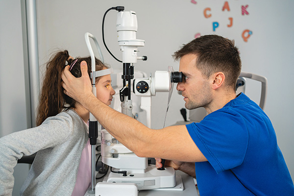Male ophthalmologist examining a girl with slit lamp