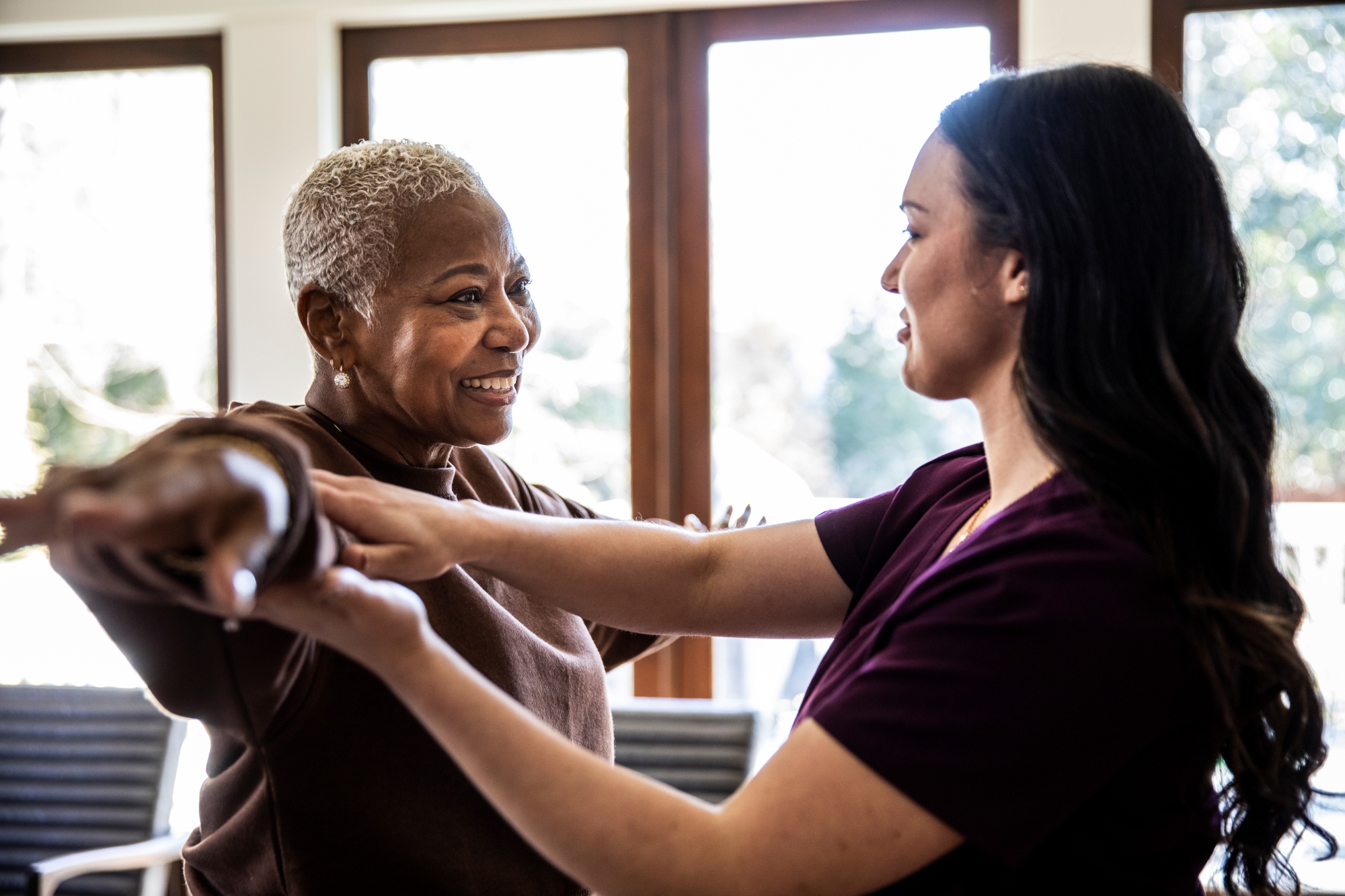 Older woman working in home with physical therapist