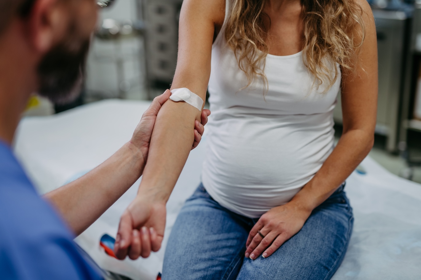 Doctor taking blood sample from pregnant woman as a part of prenatal care