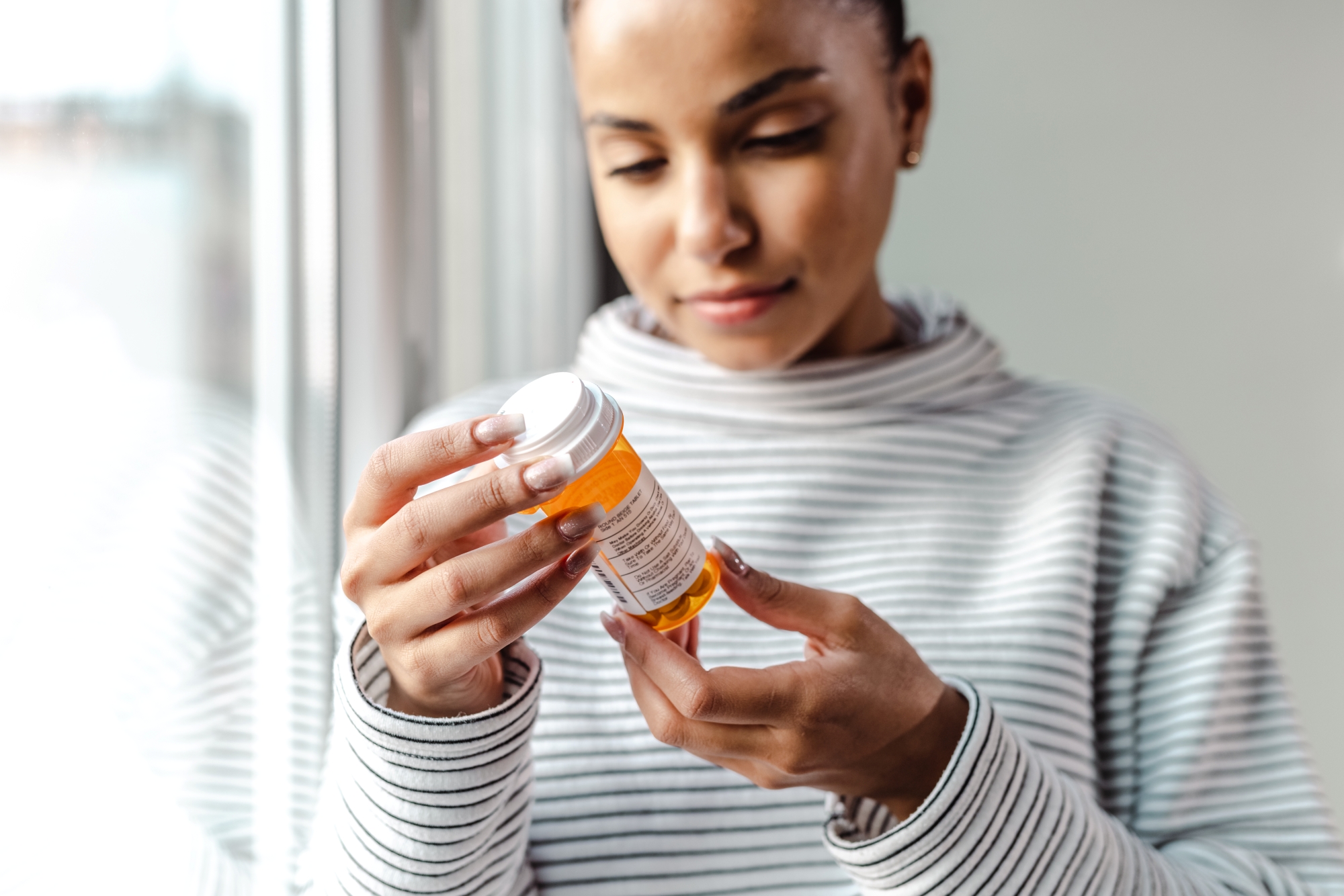 Woman looking at label on prescription bottle