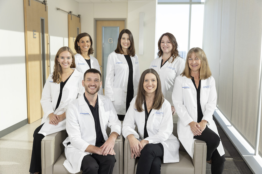 A group photograph of the professional voice care team, featuring several healthcare providers in white coats, seated and standing together.