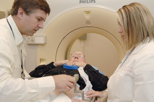 Healthcare professionals assisting an elderly patient during a medical imaging procedure, likely an MRI.