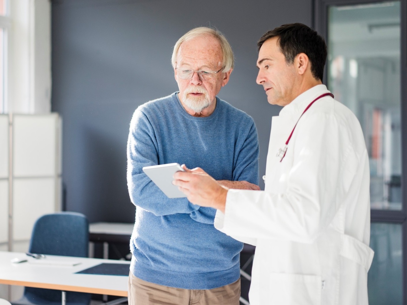 Male patient and doctor looking at information on tablet