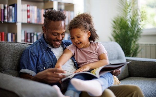father reading to daughter on a couch