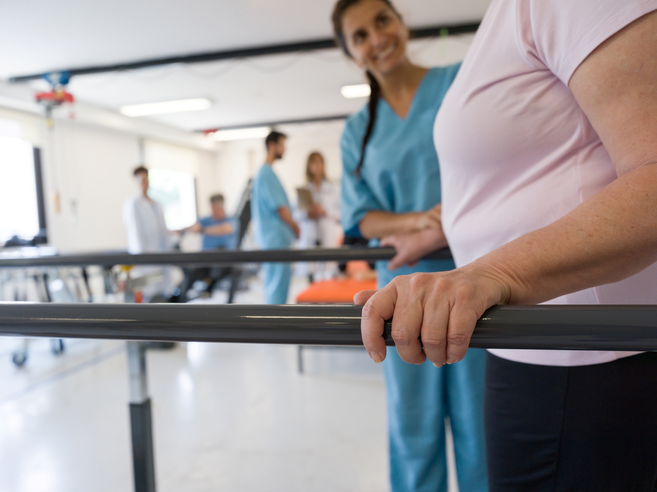 Woman using bars to walk during physical therapy session