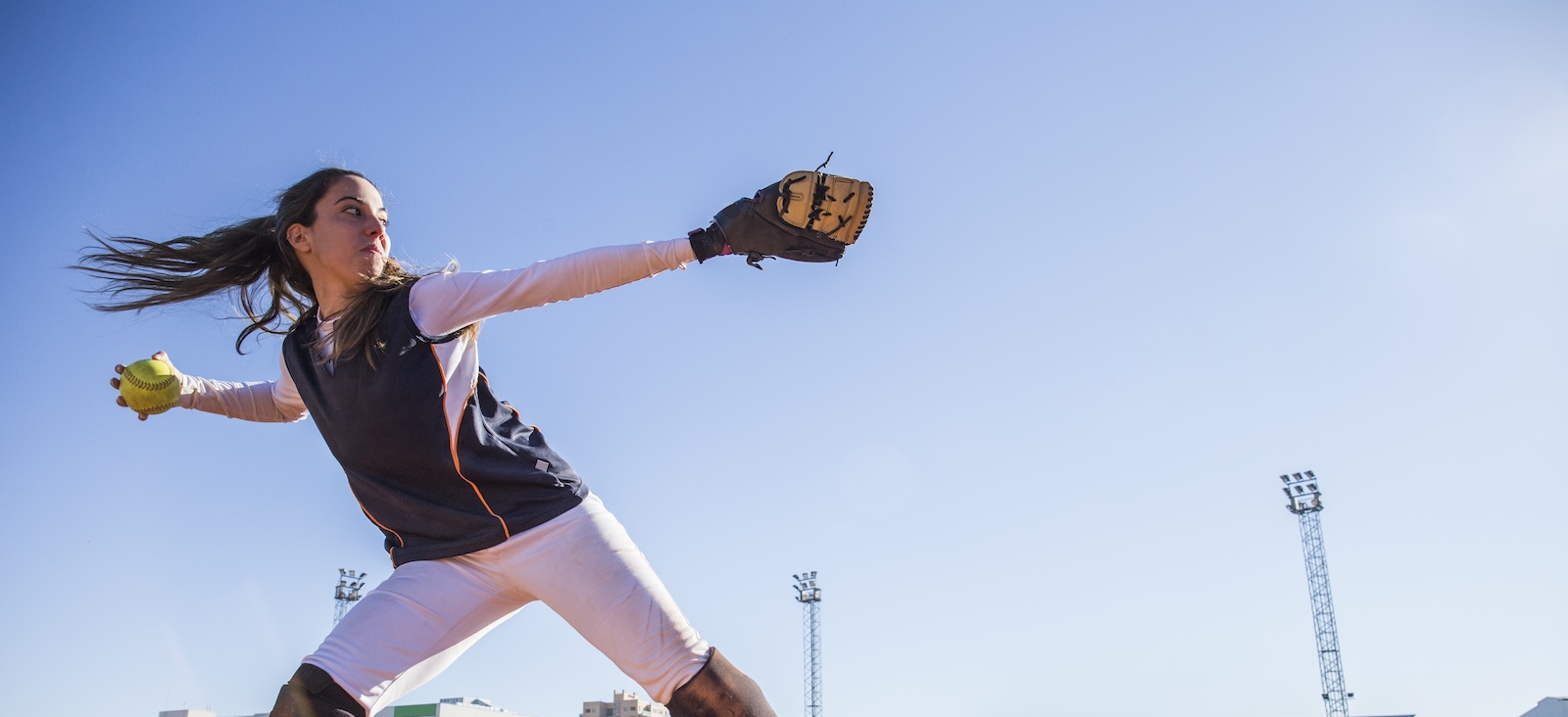 Woman in softball uniform throwing a softball