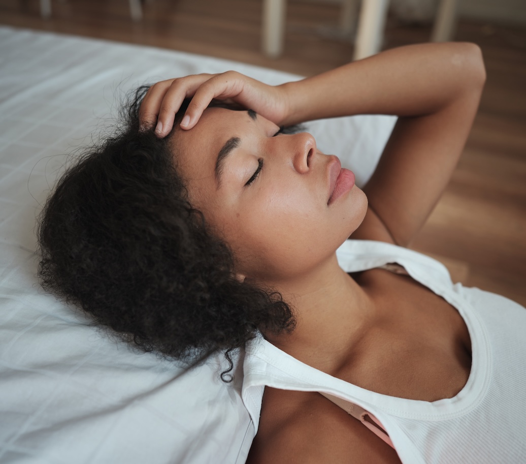 Woman laying down with hand on brow