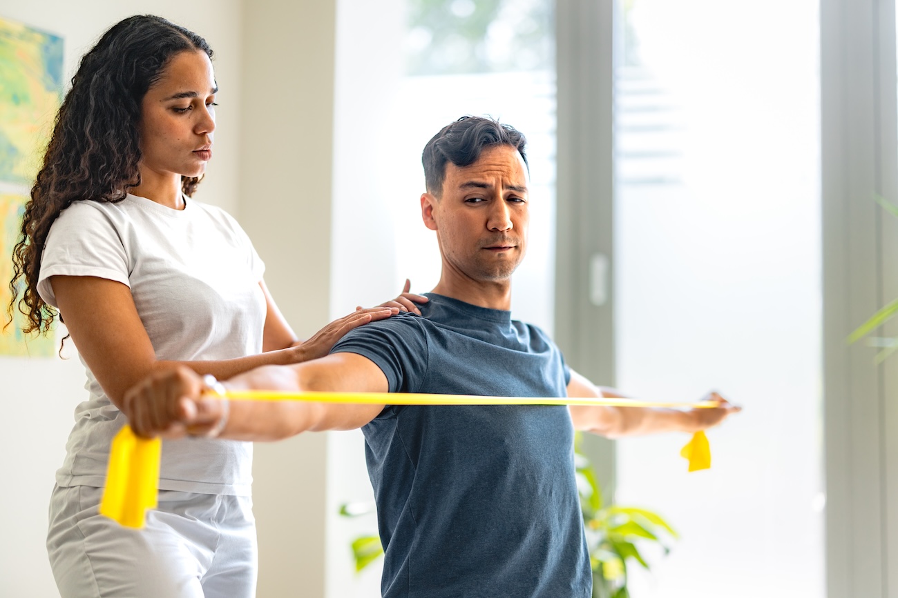 Man doing shoulder rehab with help from physical therapist