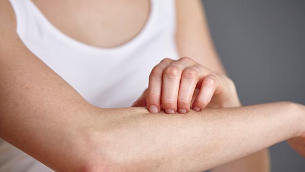 Close up of a woman scratching her forearm.