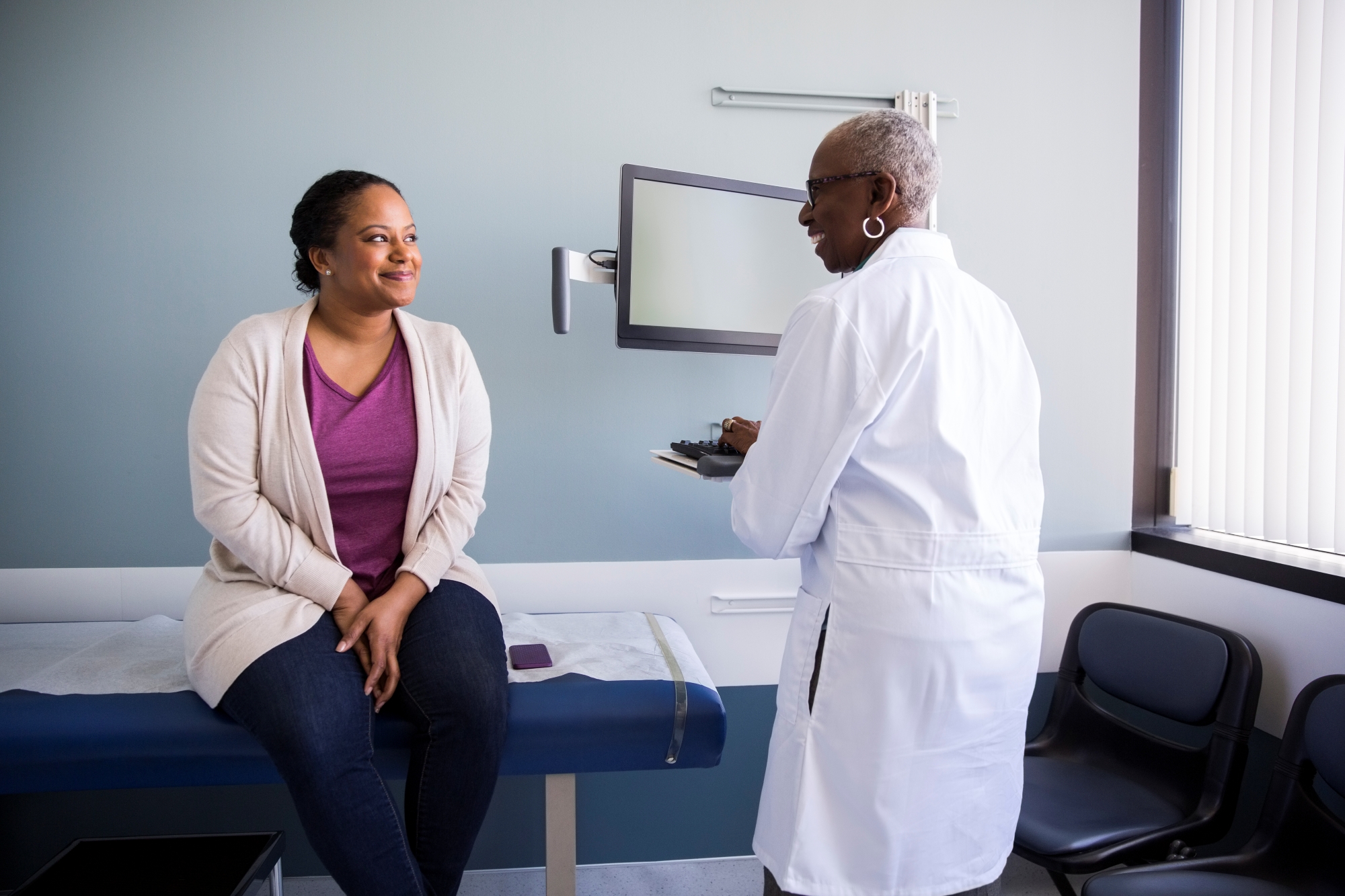 Female patient talking with female doctor in medical exam room