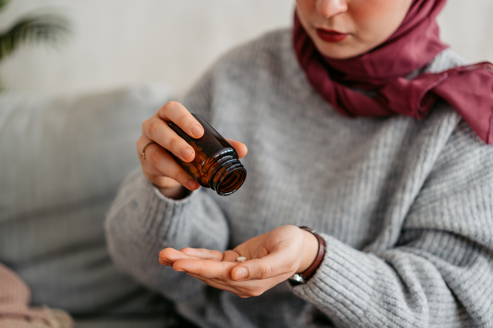 Woman shaking out pills from bottle into outstretched hand
