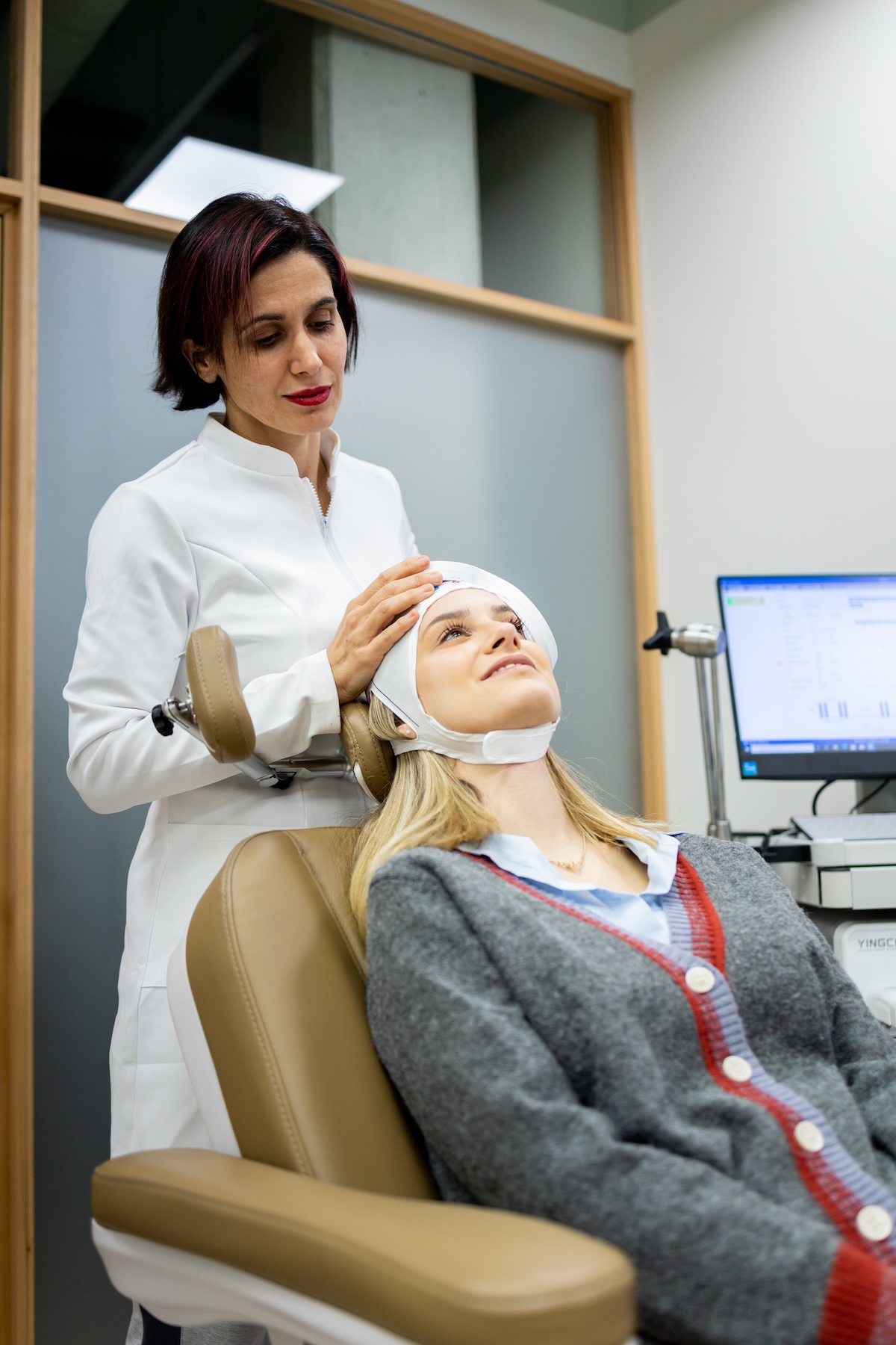 Psychiatrist placing a transcranial magnetic stimulation device on a female patient