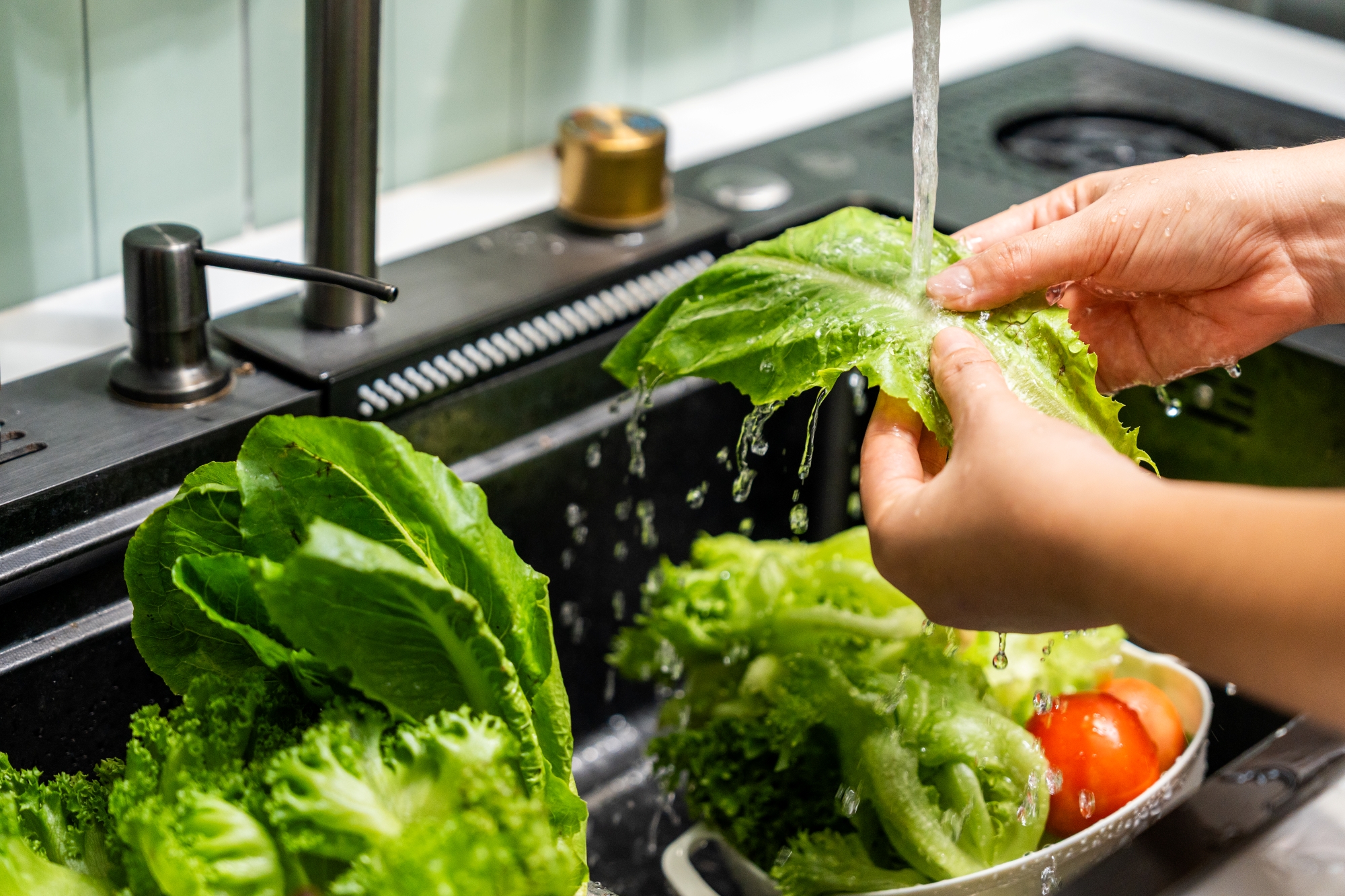 Lettuce leaves being washed in kitchen sink